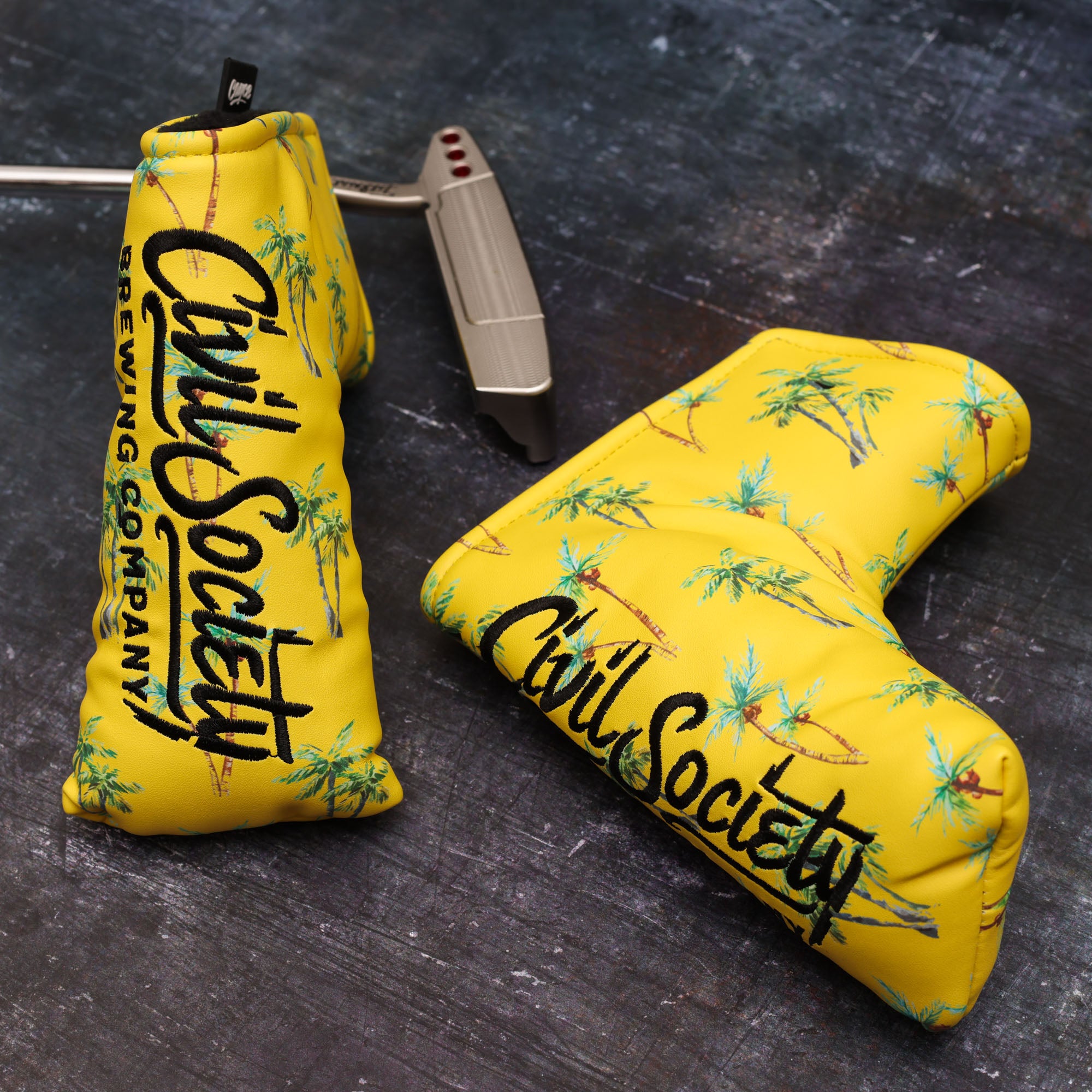 bright yellow custom golf head covers for civil society brewing company made by cayce golf standing on a grundge background with a scotty cameron blade putter